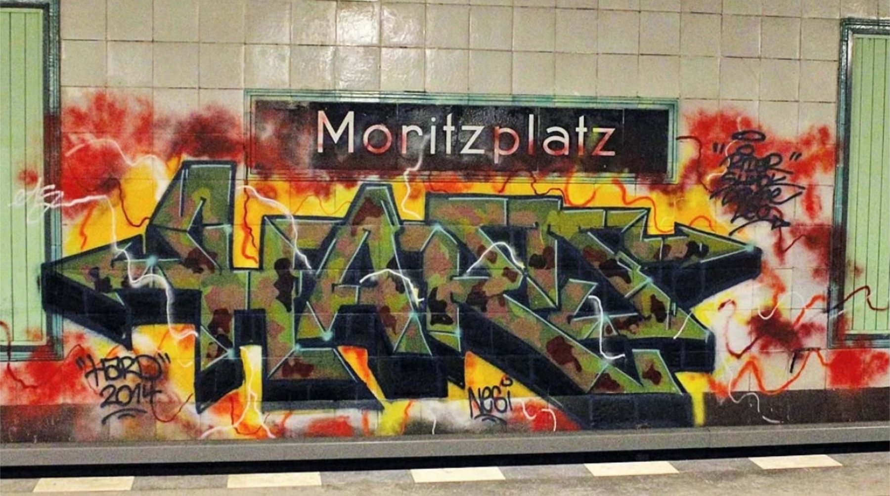 A large graffiti piece on the tiled platform wall of Moritzplatz station, Berlin